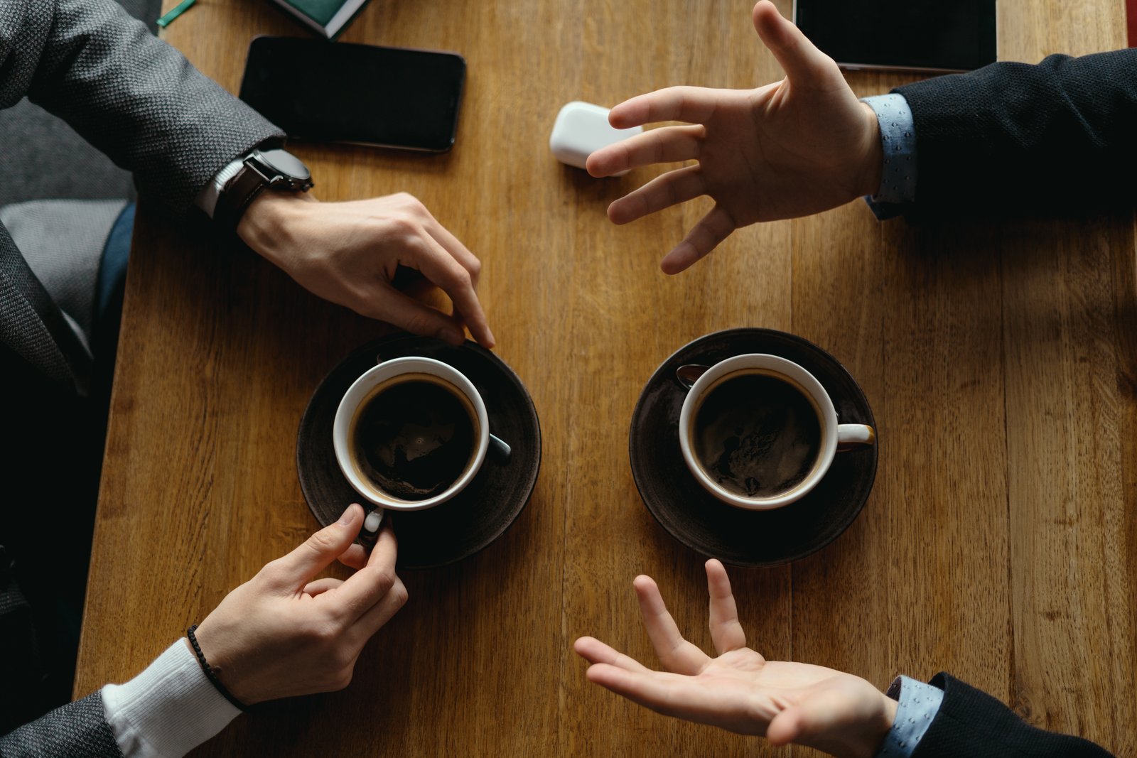Starbucks Case Study, two men meeting in starbucks coffee shop, showing coffee cups on the table with their hands